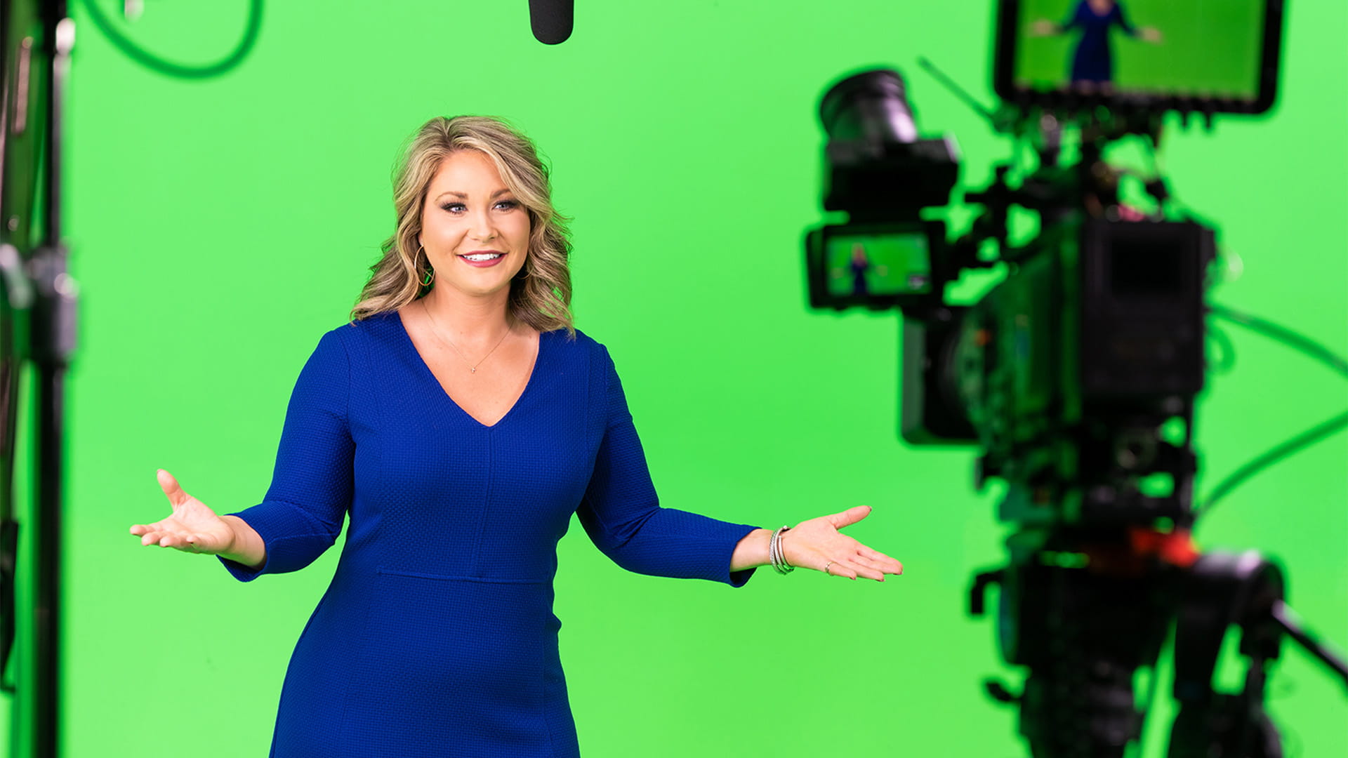 Meaghan Thomas, Broadcast Meteorologist, wearing Signia hearing aids in front of green screen